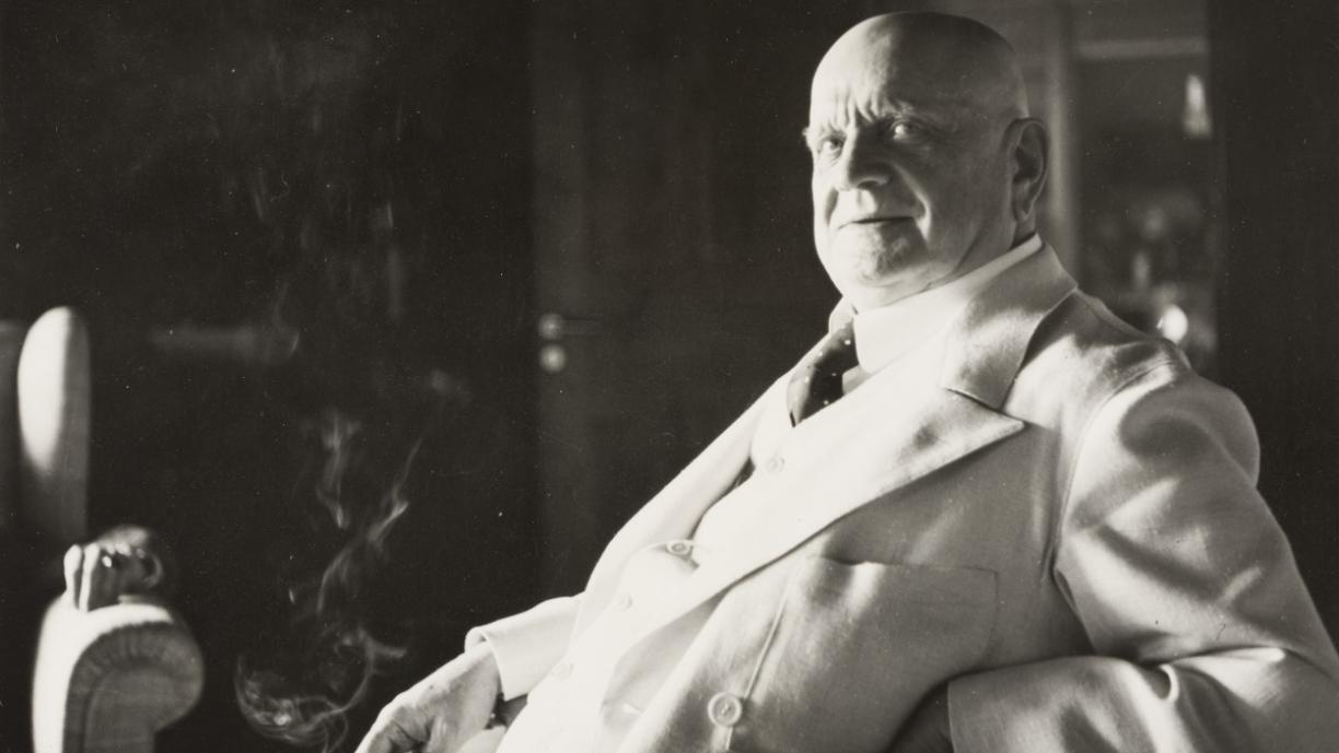 Jean Sibelius istuu tuolilla ja hymyilee