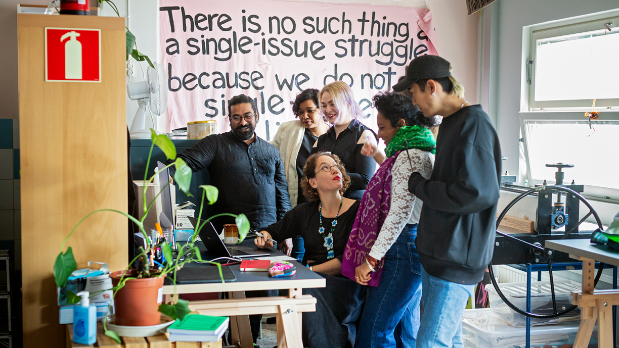 Taideyhteisön jäsenet katsovat tietokoneen näyttöä.