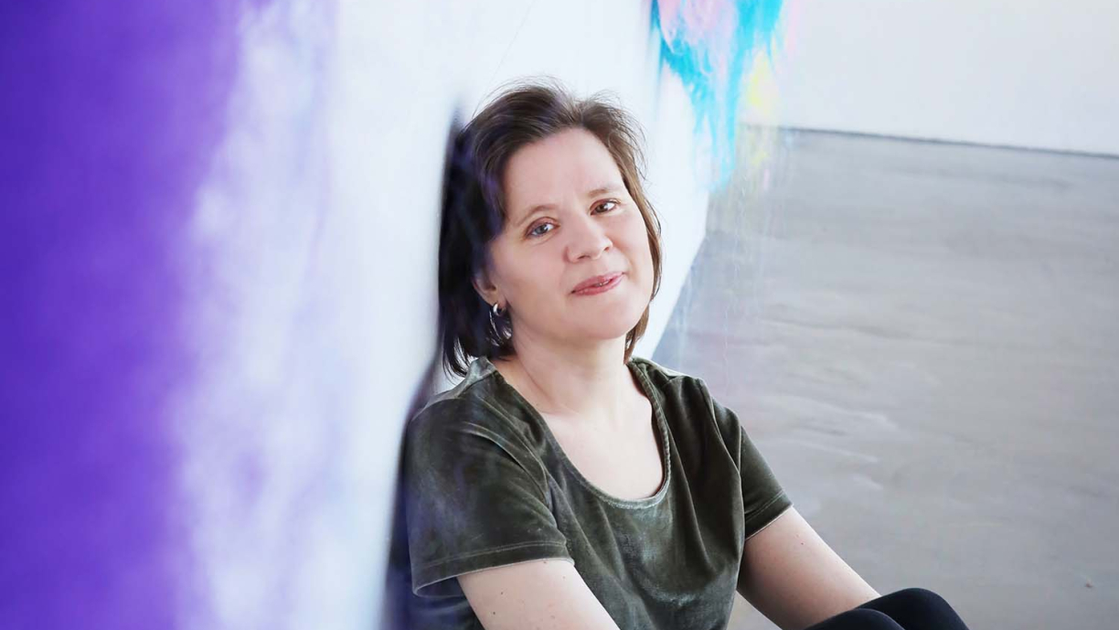 Riikka Talvitie istuu ja nojaa seinään.