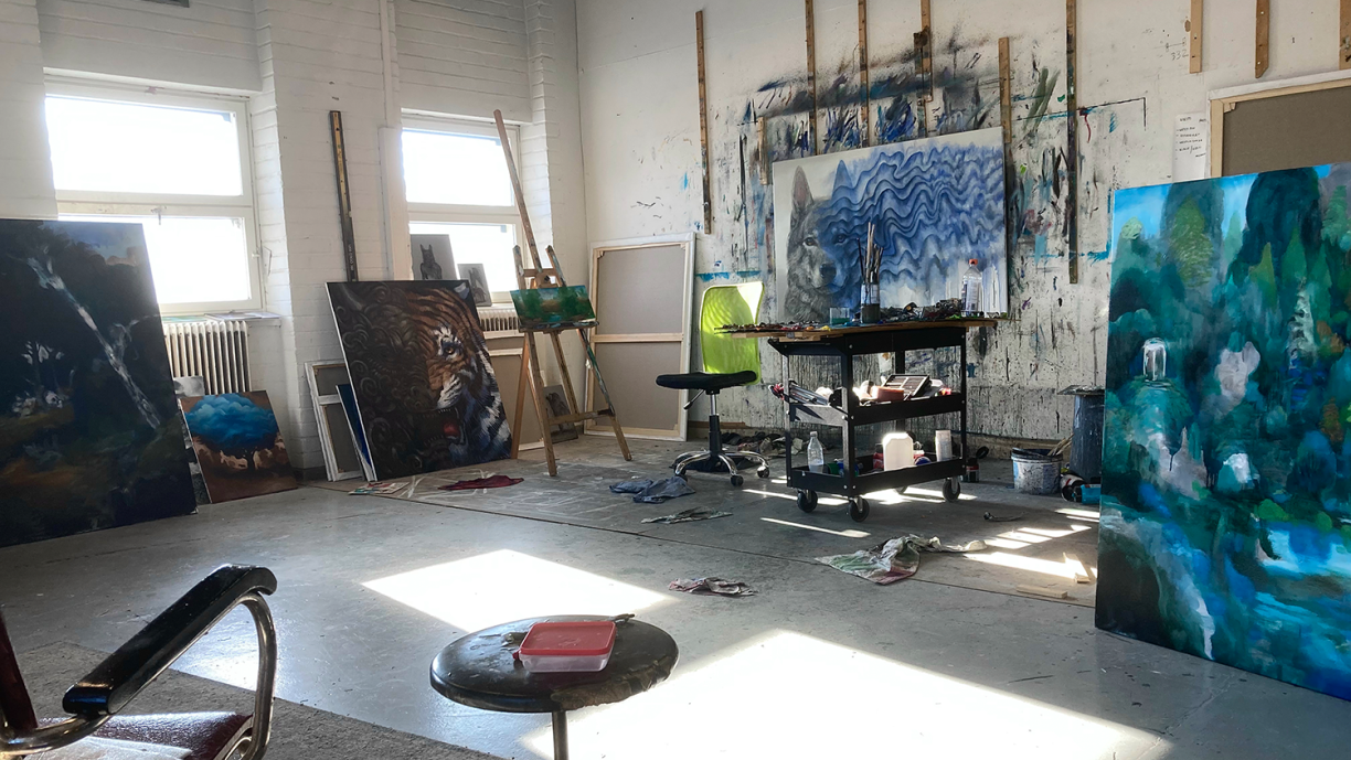 Taiteilijan työhuoneella näkyy keskeneräisiä maalauksia.