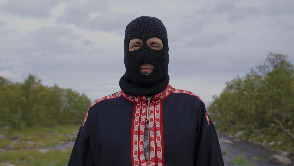 Sámi Hustler seisoo ulkona musta kommandopipo päässään ja katsoo kohti kameraa