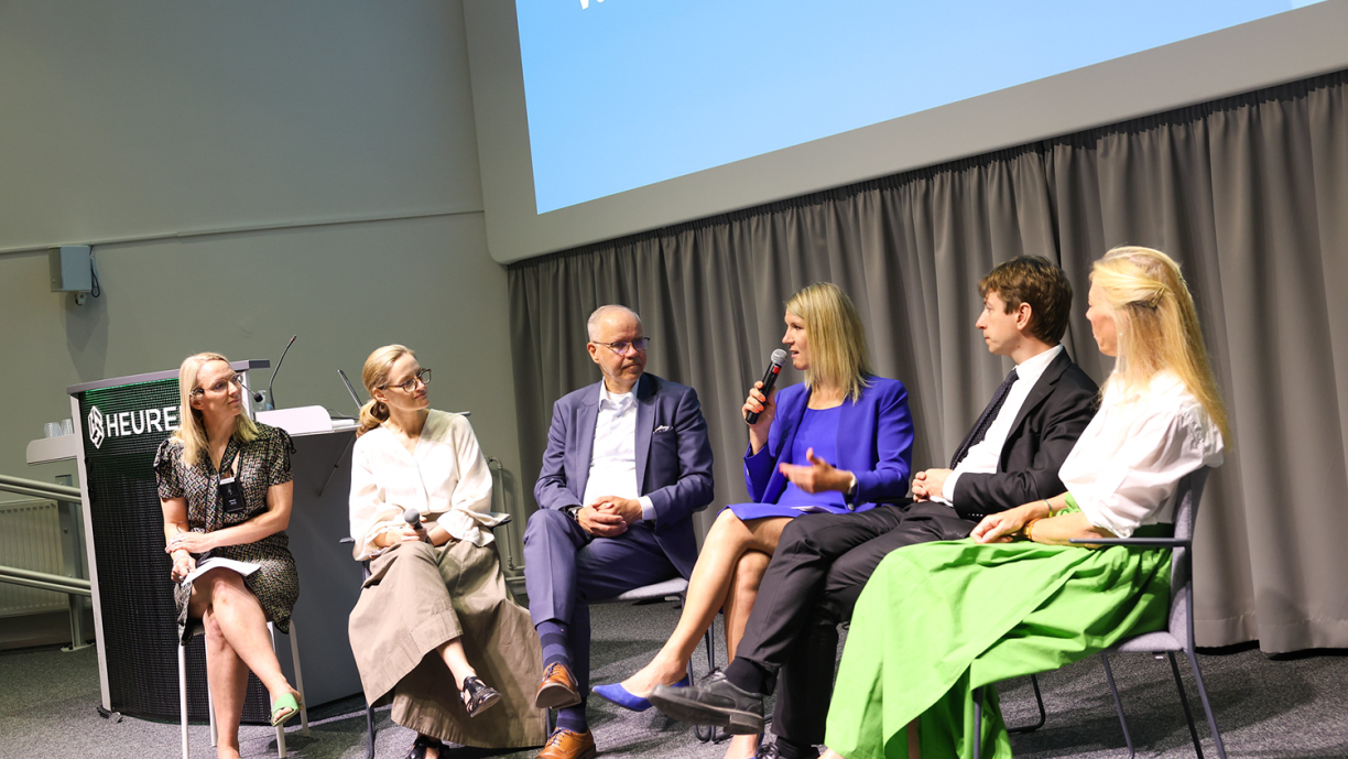 Panelistit istuvat tuoleilla lavalla.