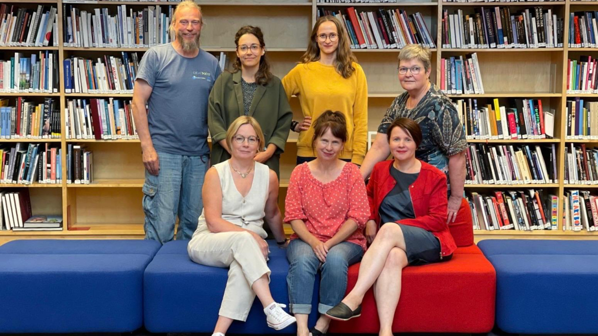 KUVATA-hanketiimi. Seitsemän henkilöä kirjahyllyn edessä.