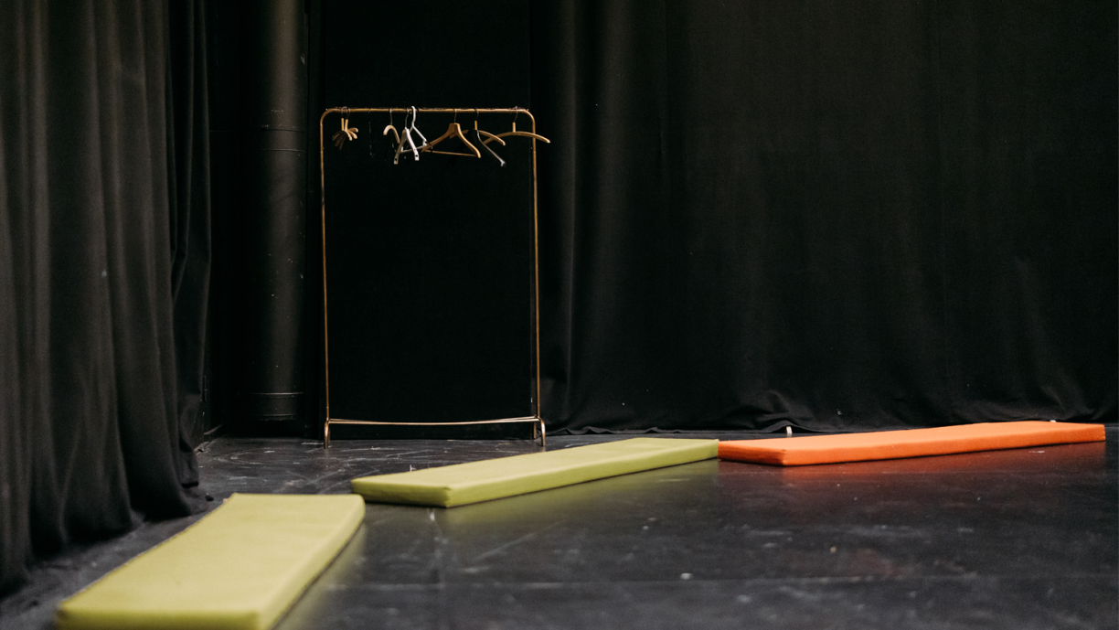 Teatterilavalla patjoja ja tyhjä vaaterekki.