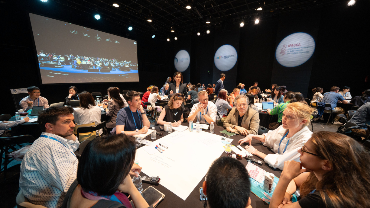 Ihmisiä keskustelemassa pyöreän pöydän ympärillä.