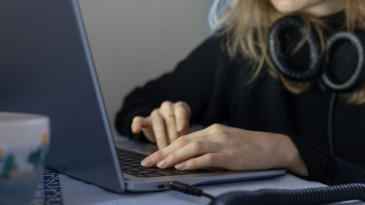 Kädet tietokoneen näppäimistöllä.