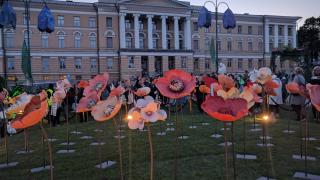 Helsingin Senaatintorilla ihmisiä kerääntyneenä suurten jalustoilla seisovien kukkaveistosten luokse.