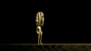 Kullanvärinen patsas, jonka pää muistuttaa saksanpähkinää tai suuria aivoja.