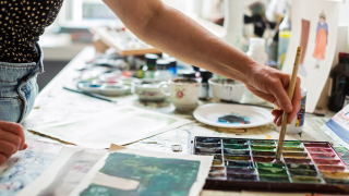 Kuvittaja ottaa väriä pensseliin