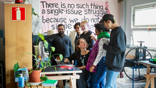 Taideyhteisön jäsenet katsovat tietokoneen näyttöä.