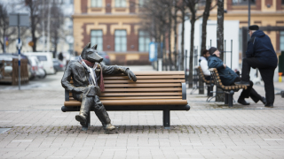 Veistos, jossa susihahmo istuu ulkona penkillä 