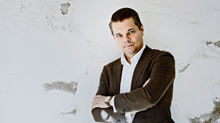 Oopperalaulaja seisoo seinän edessä ja on ristinyt kädet vatsansa eteen.