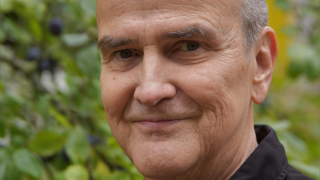 Taiteilija katsoo kameraan hymyillen