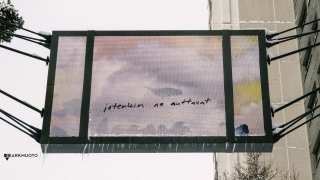 Kadun yläpuolella roikkuva taulu, jossa lukee teksti: "jotenkin ne auttavat".