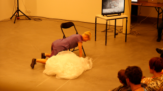 Hanna Kahrola on kontillaan lattialla tanssiesityksessä.