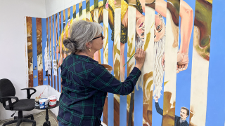 Taiteilija työskentelee maalauksensa ääressä.