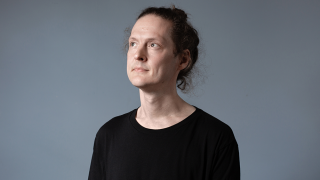 Antti Tolvi katosoo ylös päin harmaan seinän edessä.