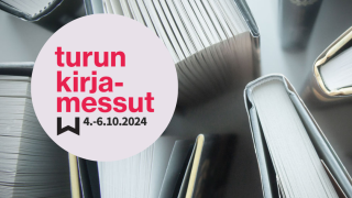 Osittain auki olevia kirjoja pystyssä, ylhäältä päin kuvattuna. Turun kirjamessujen logo punaisella vaaleanpunaisen ympyrän sisällä. 