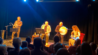 Lavalla neljä esiintyjää, joita yleisö katsoo. 