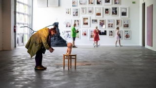 Taidenäyttelyn kävijä katselee lähietäisyydeltä pientä puista veistosta