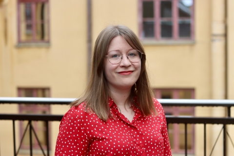 Henkilö hymyilee kaiteen edessä.