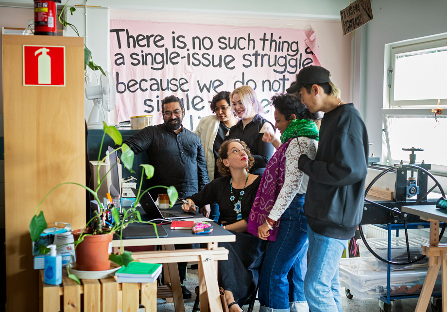 Taideyhteisön jäsenet katsovat tietokoneen näyttöä.