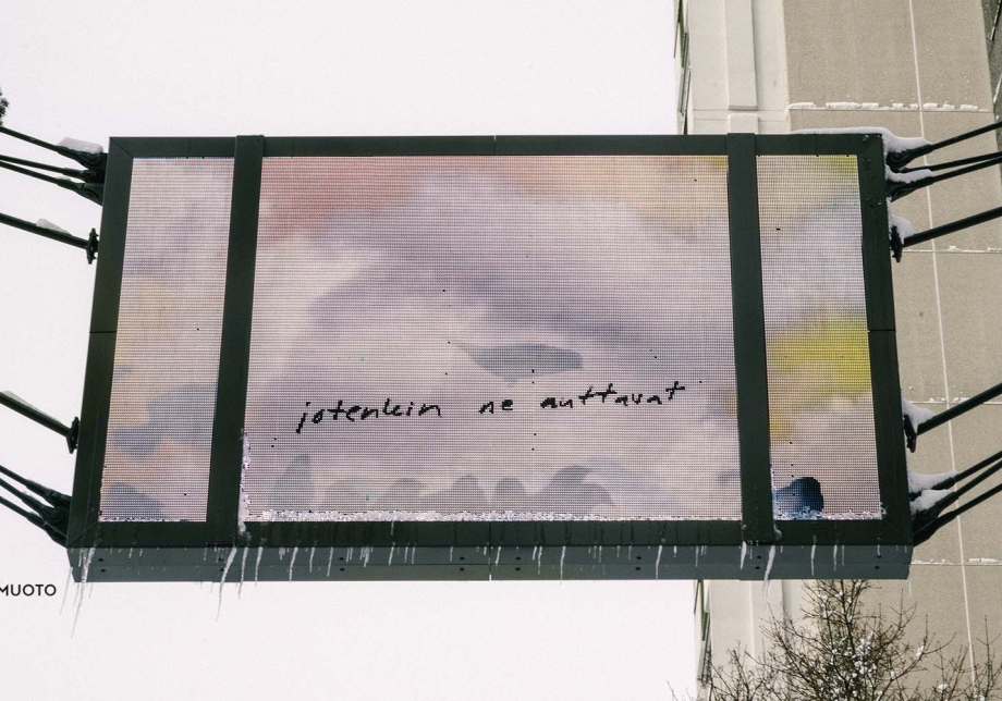 Kadun yläpuolella roikkuva taulu, jossa lukee teksti: "jotenkin ne auttavat".