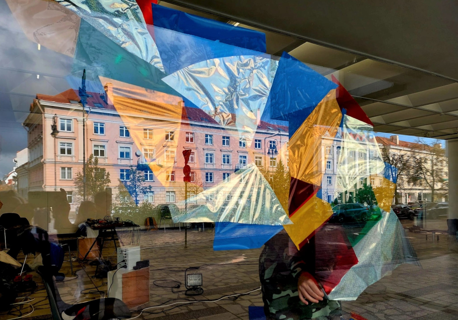 Ett konstverk bakom ett fönster. Fönstret reflekterar byggnaden bakom.