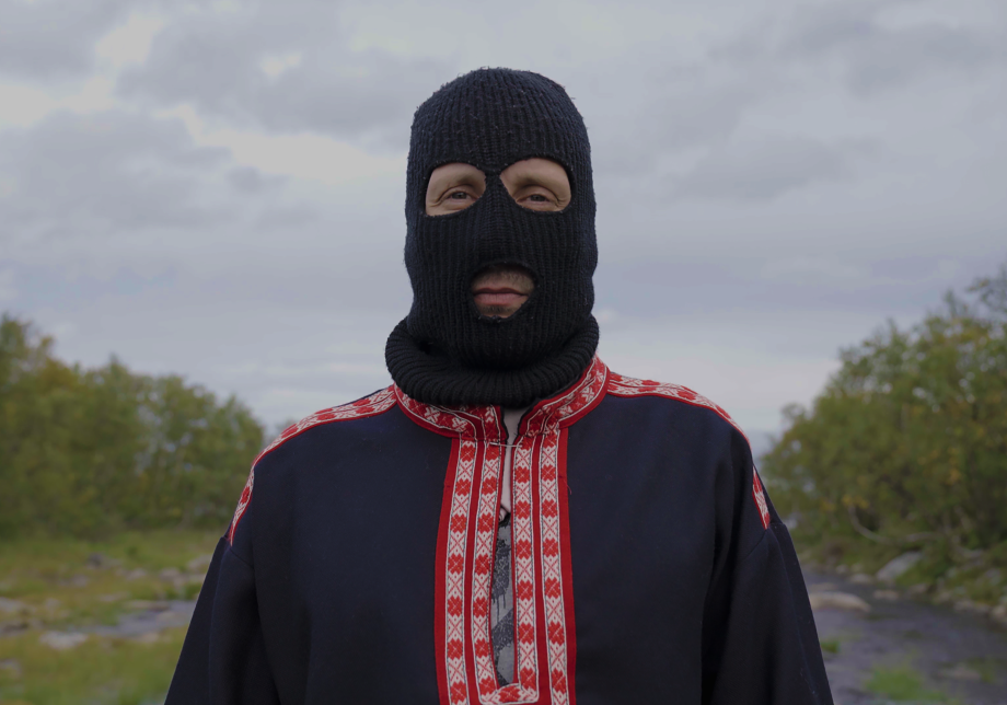 Sámi Hustler står ute med en svart kommandoluva på sig och tittar in i kameran.