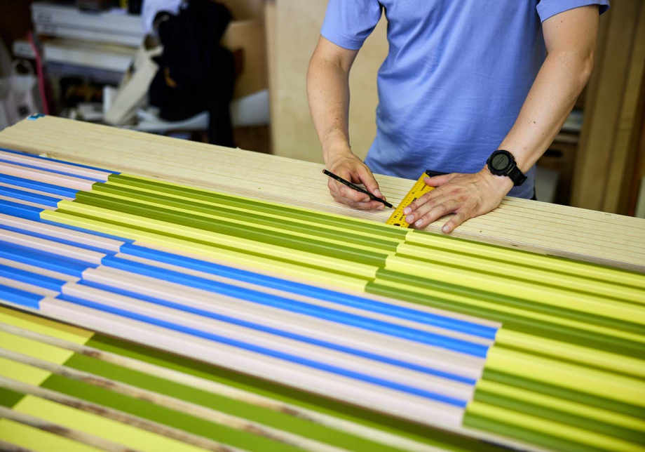 Henkilö mittaa viivoittimella teosta.