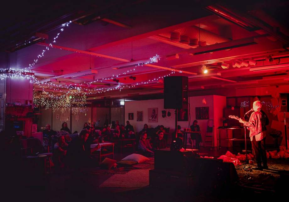 Yleisö katsoo kitaran kanssa lavalla olevaa esiintyjää.