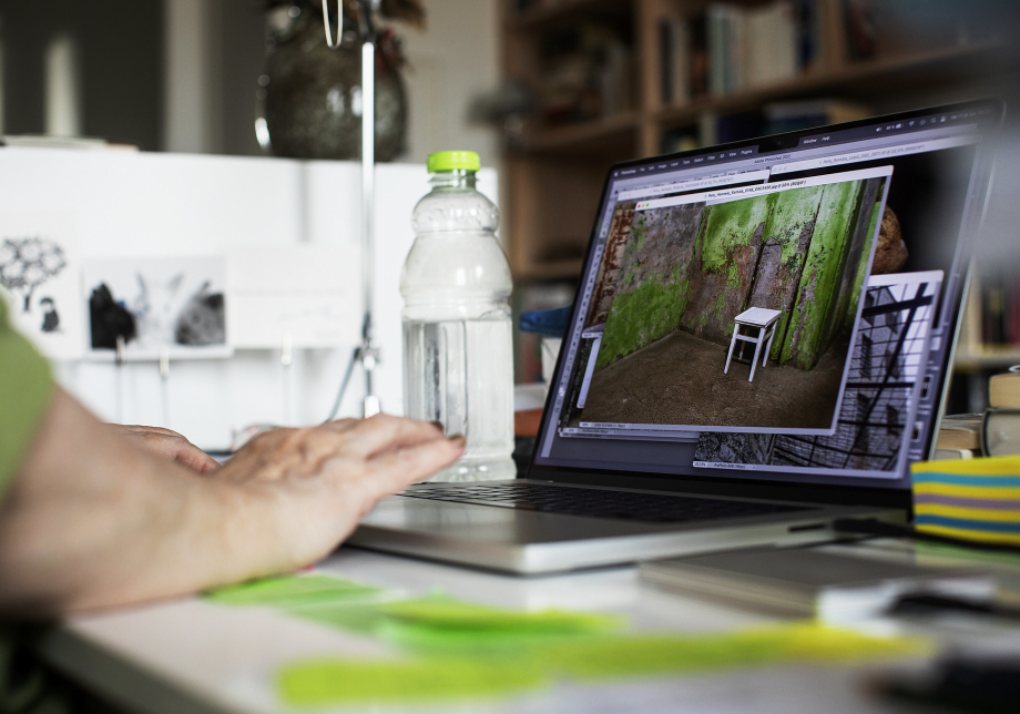 Tietokoneella auki kuvankäsittelyohjelma sekä valokuva tuolista ja rapistuneesta seinästä.