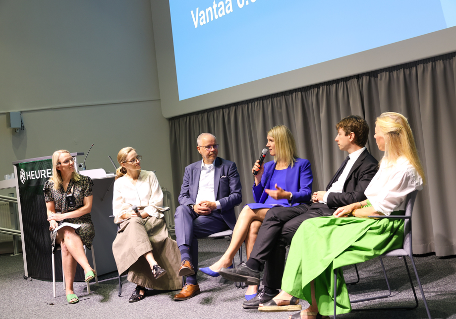 Panelistit istuvat tuoleilla lavalla. 