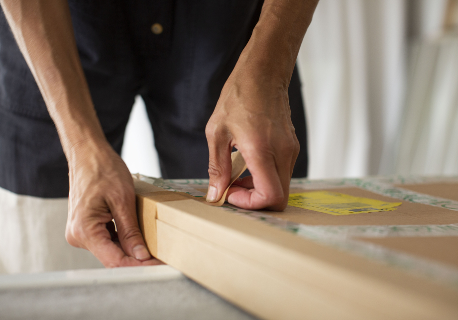 Lähikuva käsistä, jotka teippaavat vanerilaatikkoa kiinni