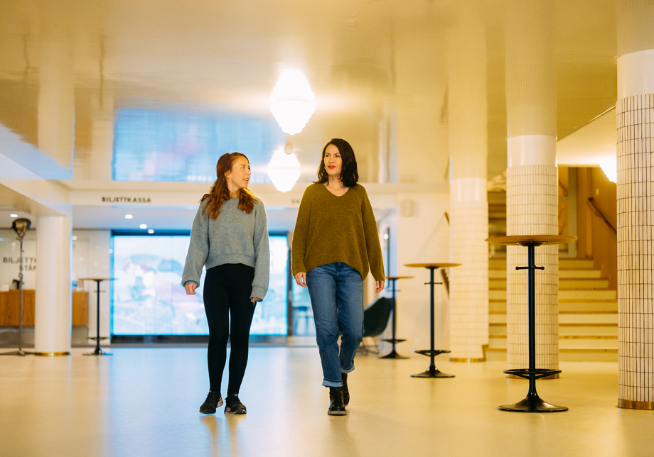 Kaksi henkilöä kävelevät teatterin aulassa.