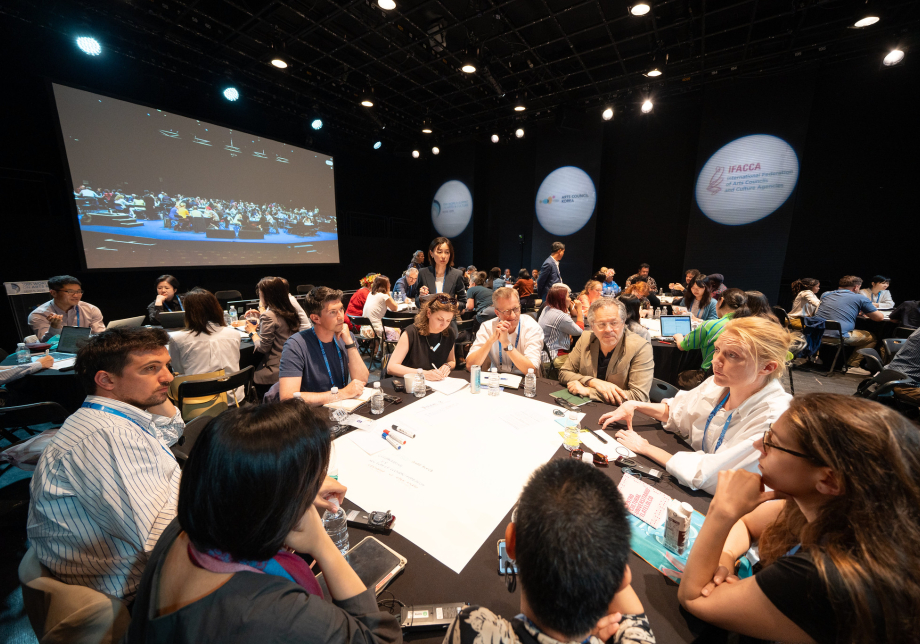 Ihmisiä keskustelemassa pyöreän pöydän ympärillä.