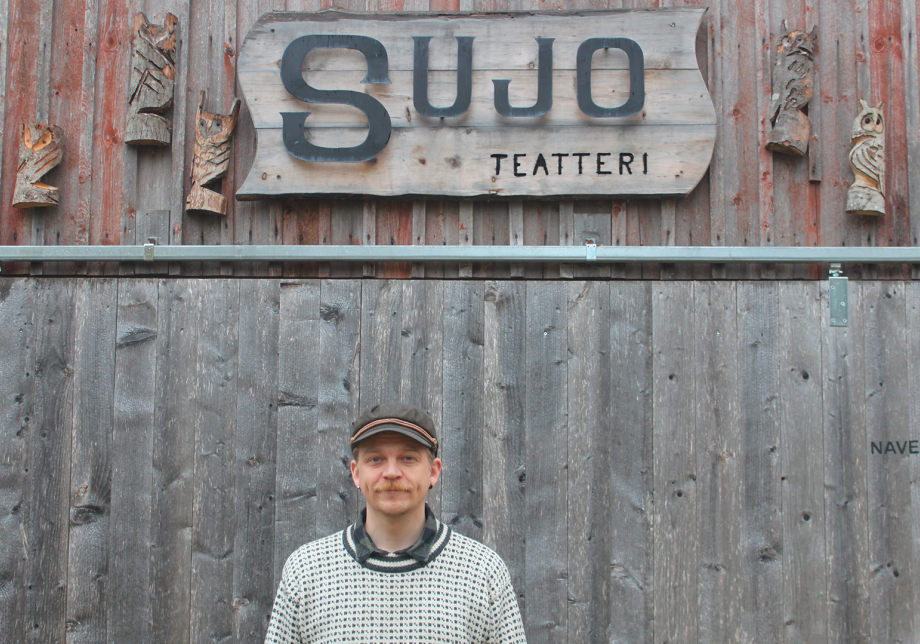 Henkilö seisoo puutalon edessä.