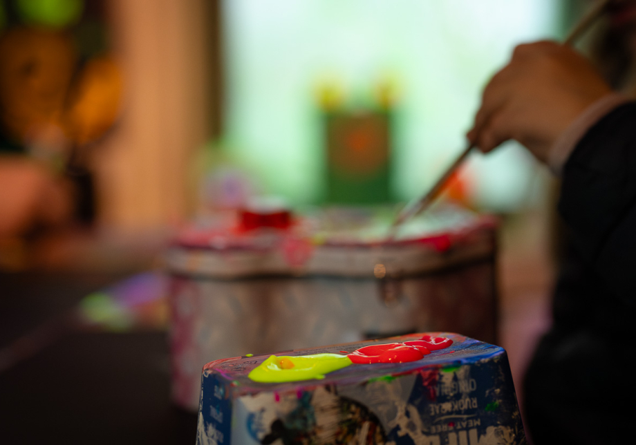 Keltaista ja punaista maalia sekoitusalustalla. Taustalla pensseli.