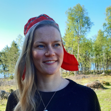 Henkilö hymyilee. Taustalla metsää.