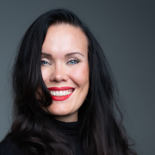 Katriina Haikala puolikuvassa harmaan taustan edessä musta paita yllään
